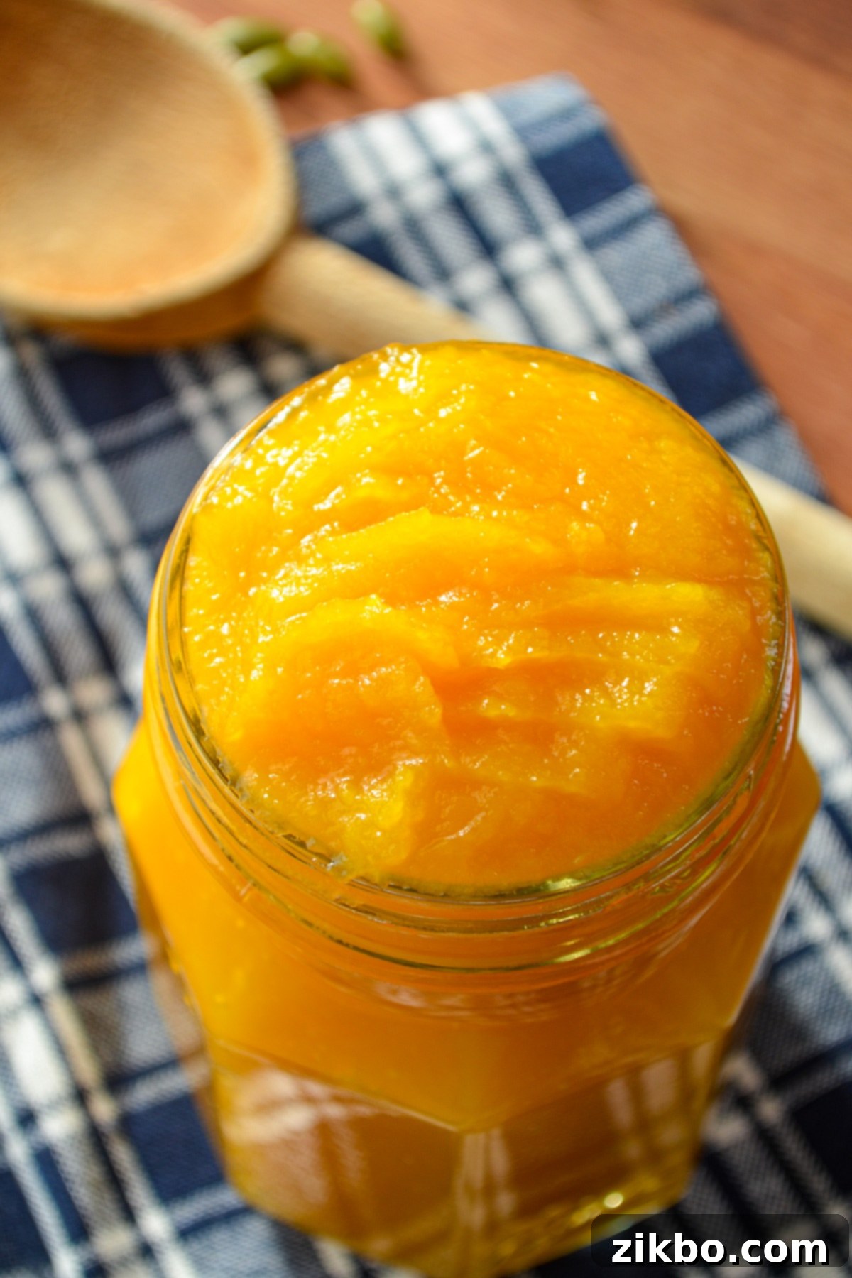 A jar of pumpkin puree, with a wooden spoon in the background.