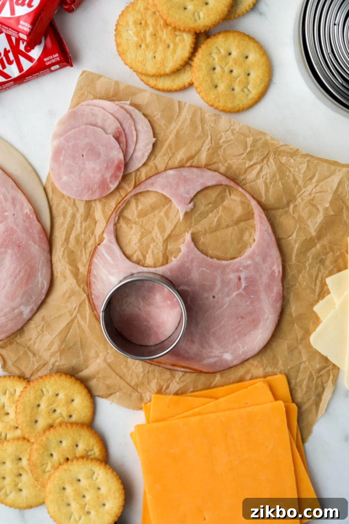 A hand using a circular cutter to slice deli meat into perfect rounds for a homemade lunchable.