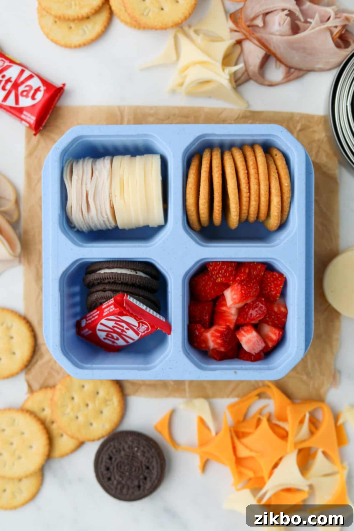 A perfectly portioned homemade lunchable container, featuring cheese, crackers, fresh fruit, and a mini chocolate bar, ready for a healthy and convenient meal.