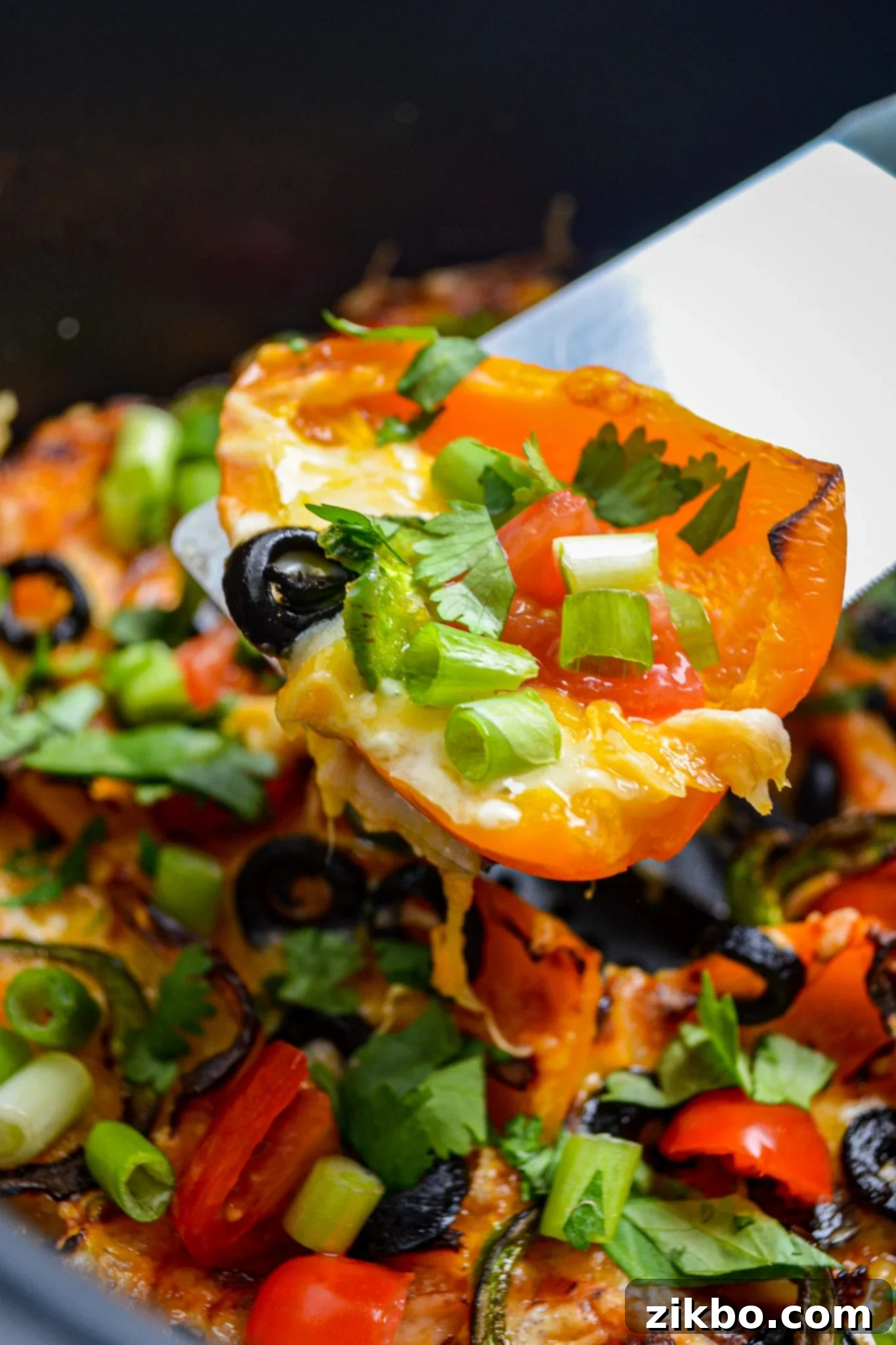 A spatula lifting out a mini pepper from an air fryer, showing the crispy texture.