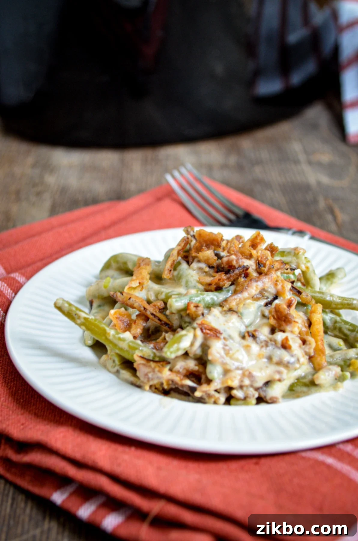 A serving of green bean casserole, with a slow cooker in the background.