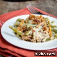 A plate of green bean casserole, served on a small plate on top of cloth napkin.