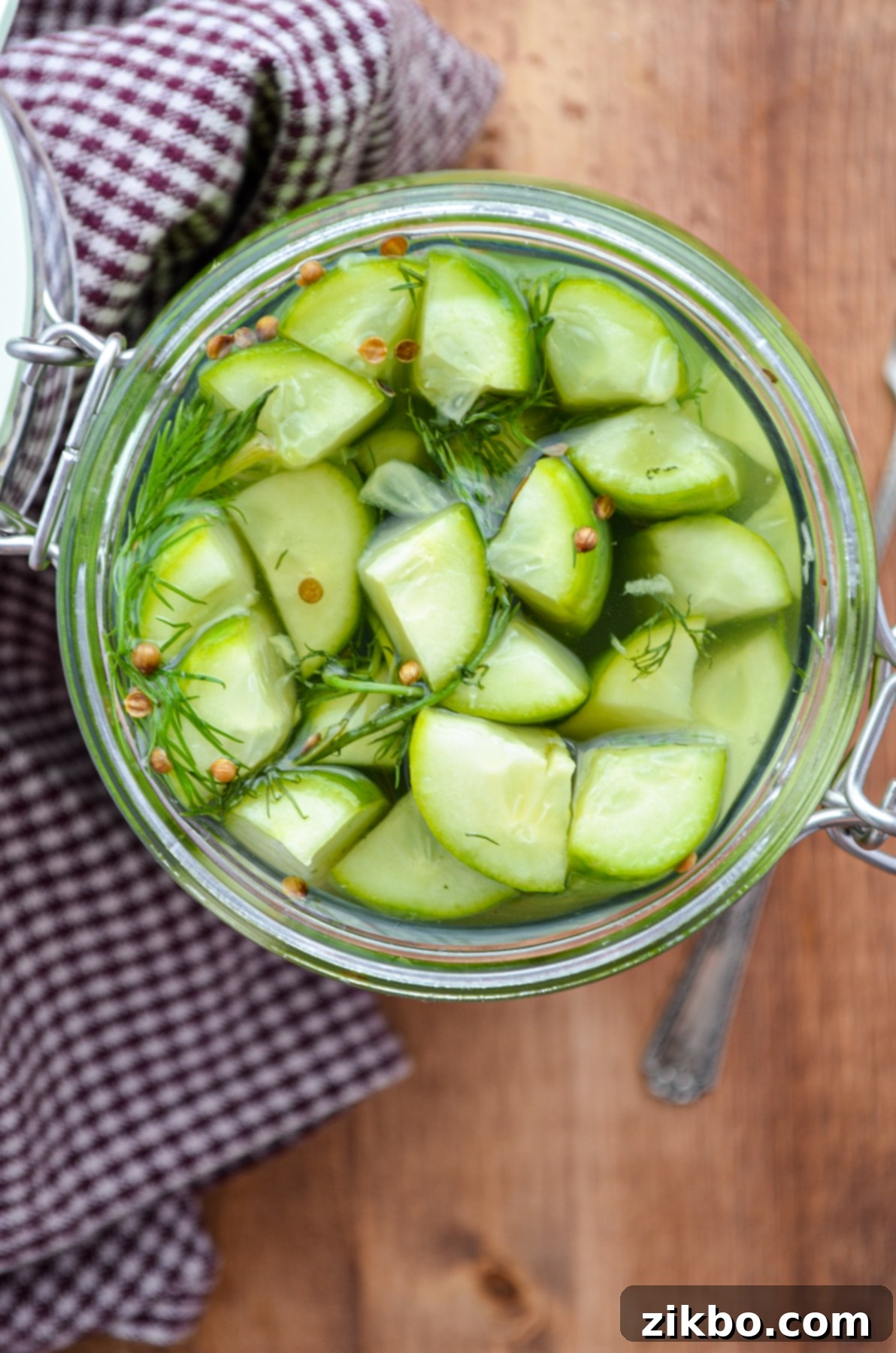 Instant Pot Fast Pickles 8 A jar of refrigerator pickles resting on a gingham napkin, ready to be enjoyed as a refreshing snack or side dish.
