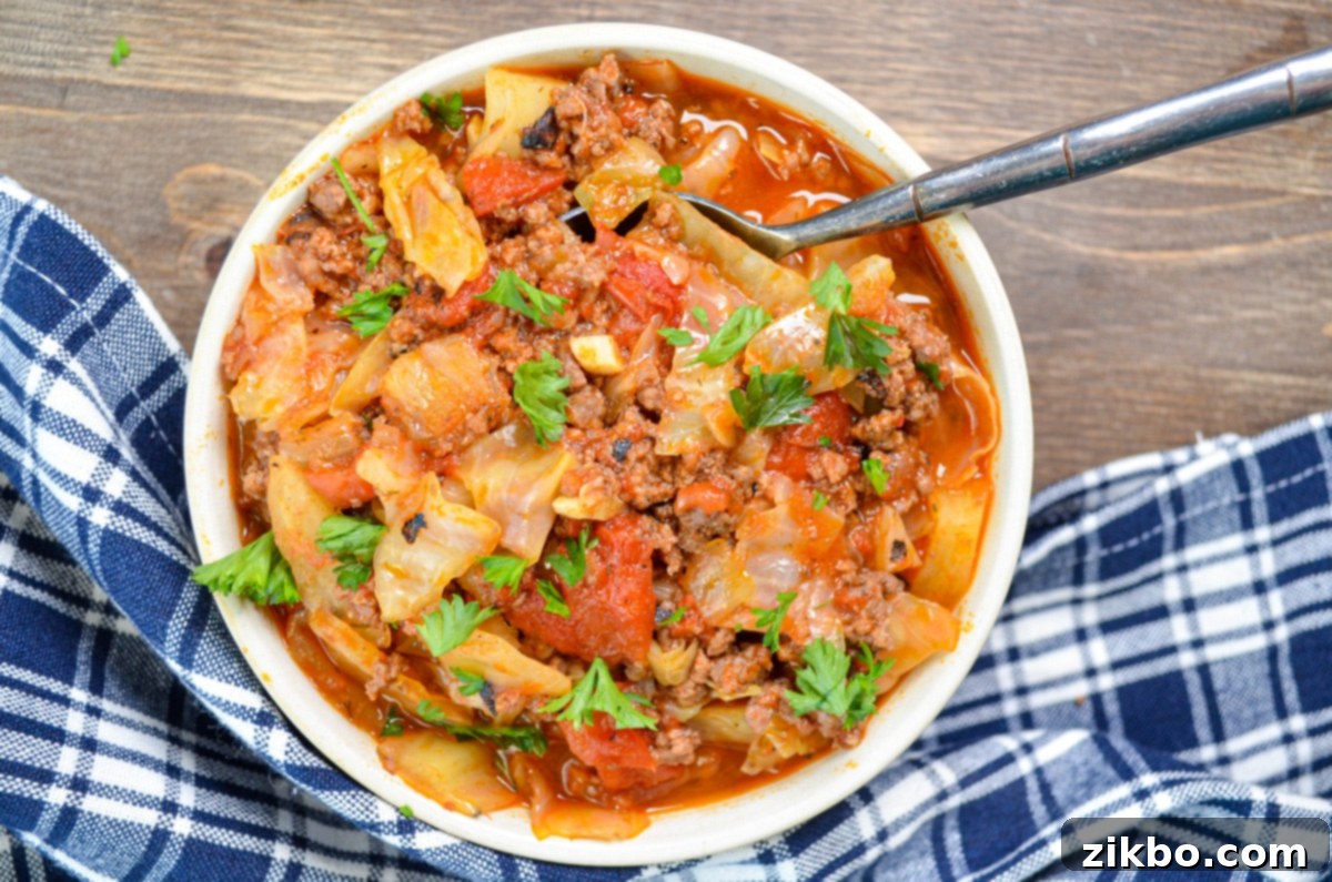 A bowl of unstuffed cabbage roll soup on a wood background.