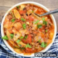 A bowl of cabbage, ground beef, and vegetables, sprinkled with parsley.