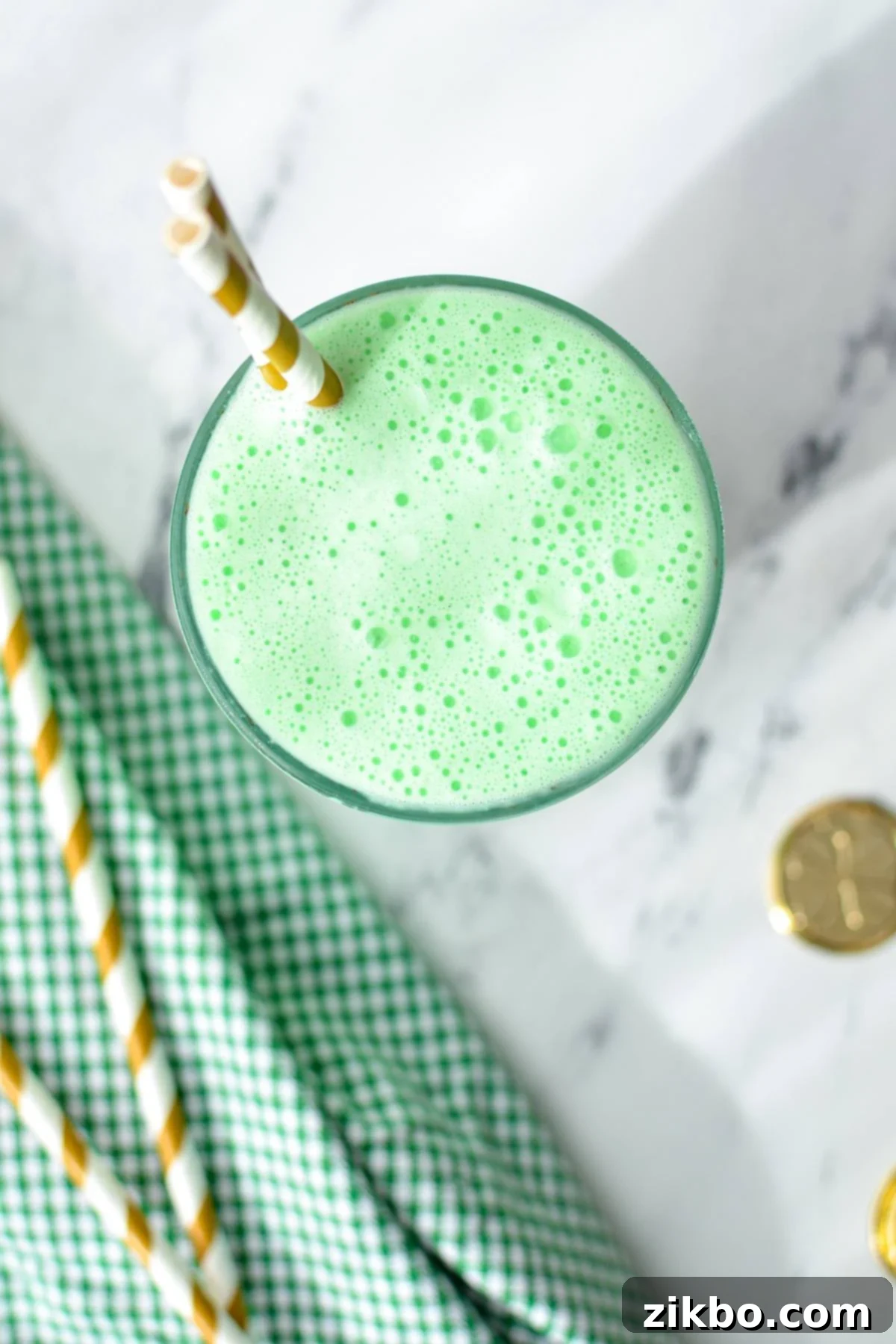 Homemade Shamrock Shake 7 An overhead shot of a vibrant green homemade shamrock shake with two gold-striped straws, showcasing its perfect color and texture.