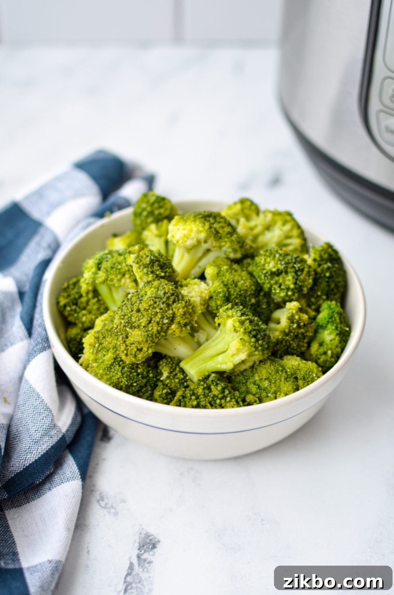 A bowl of broccoli resting on a counter with an Instant Pot in the background.