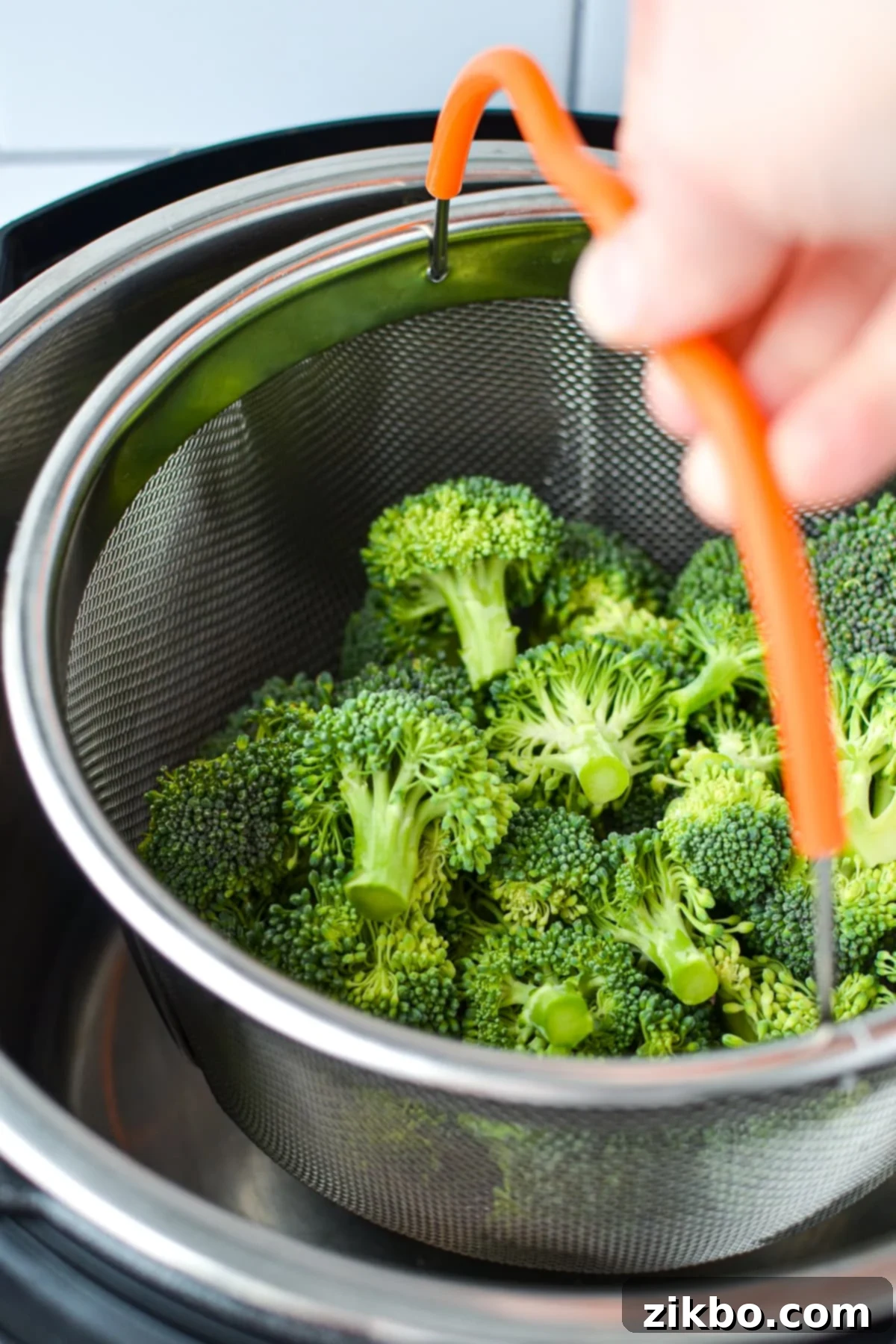 Lowering a steamer basket filled with broccoli into an Instant Pot.