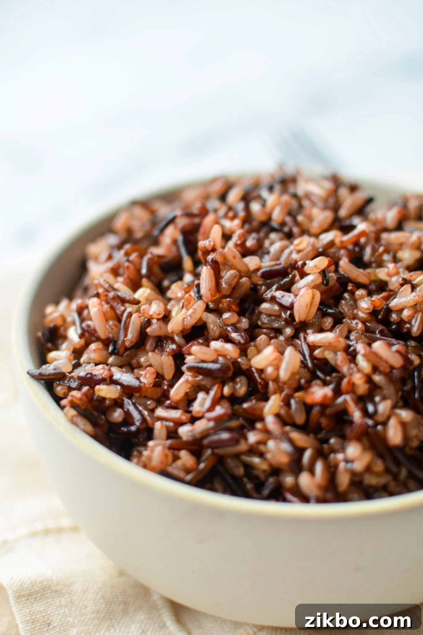 A beautifully presented bowl of perfectly cooked wild rice blend, resting on an elegant cloth napkin, ready to be served as a healthy and flavorful side dish.