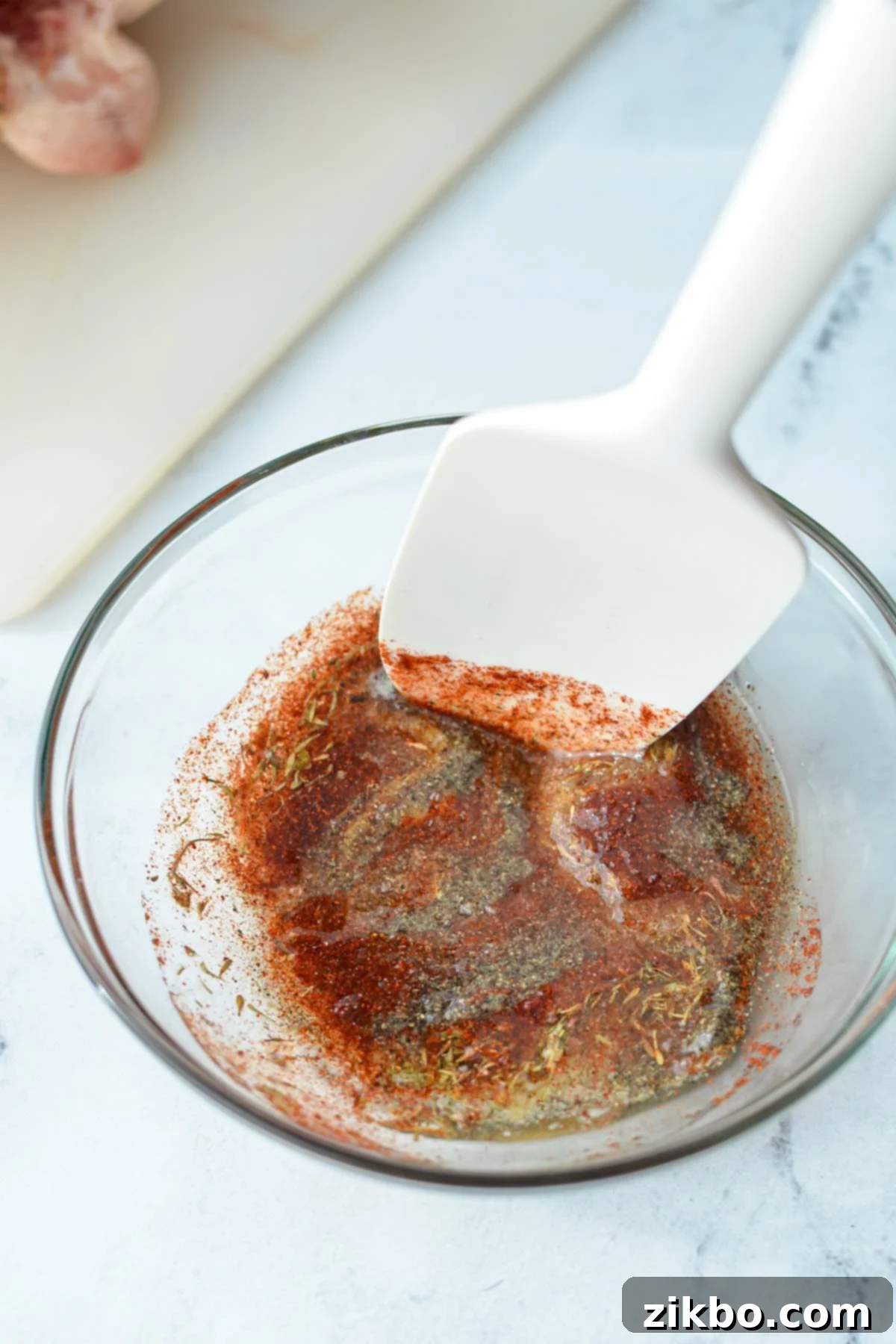 A small bowl containing a well-blended spice rub and oil mixture, forming a paste.