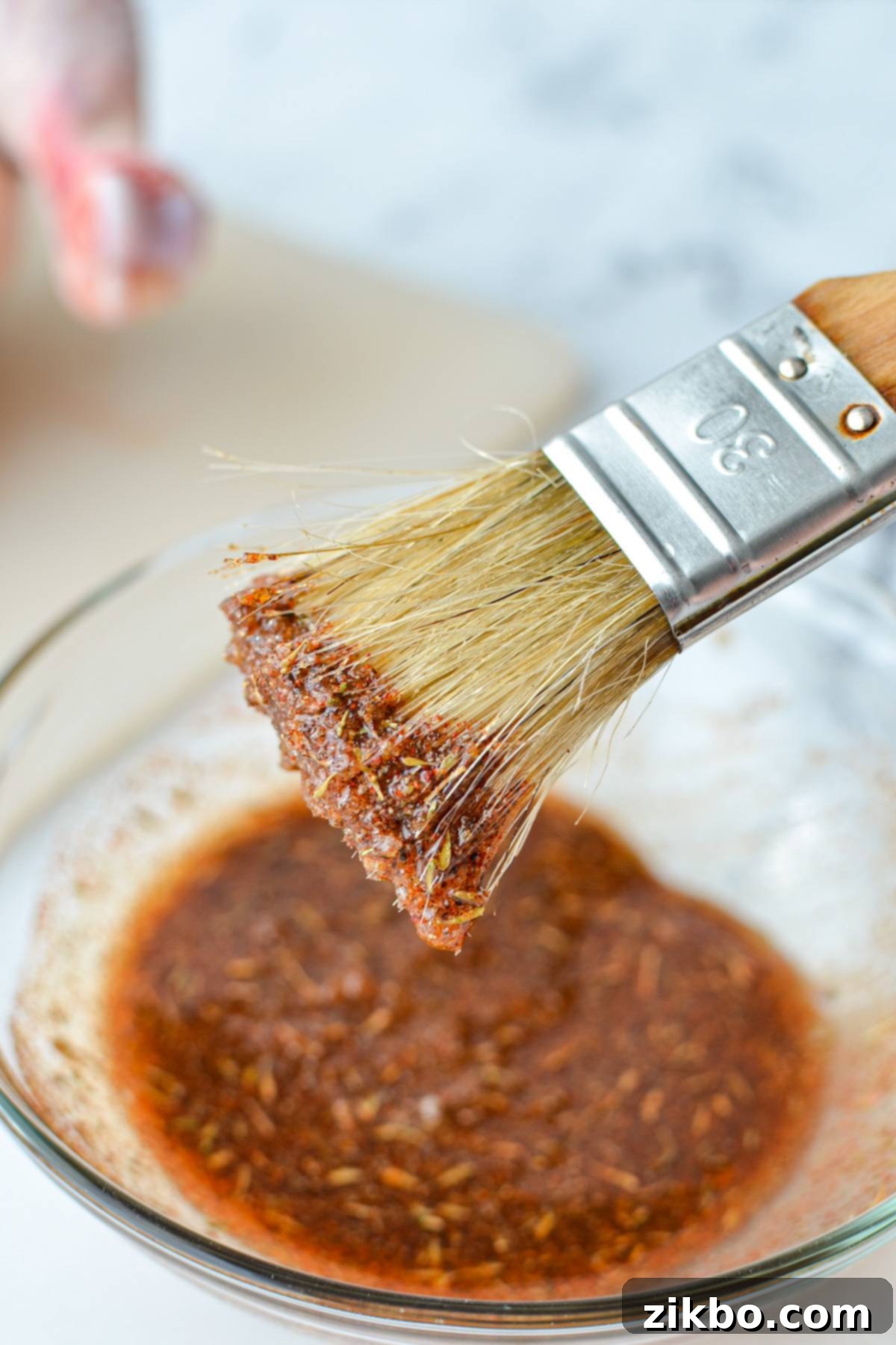 A small bowl of seasoning and oil paste, with a basting brush coated in the rub.