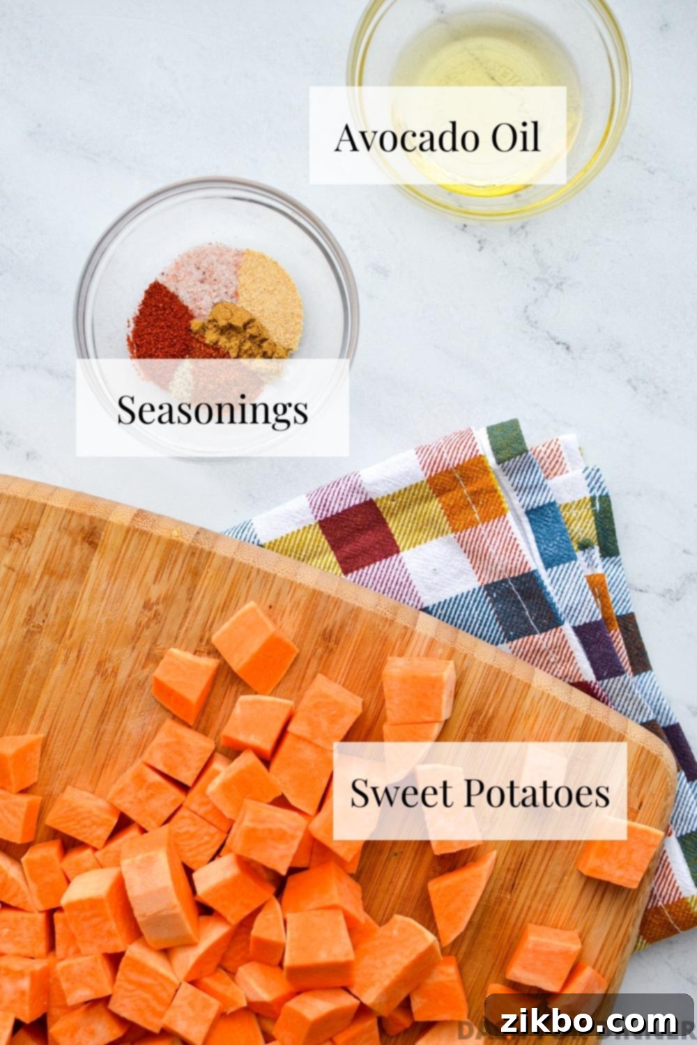 Crispy Air Fryer Sweet Potato Cubes 3 A flat lay of all the fresh ingredients needed to make air fryer roasted sweet potato chunks: whole sweet potatoes, avocado oil, and various spices.