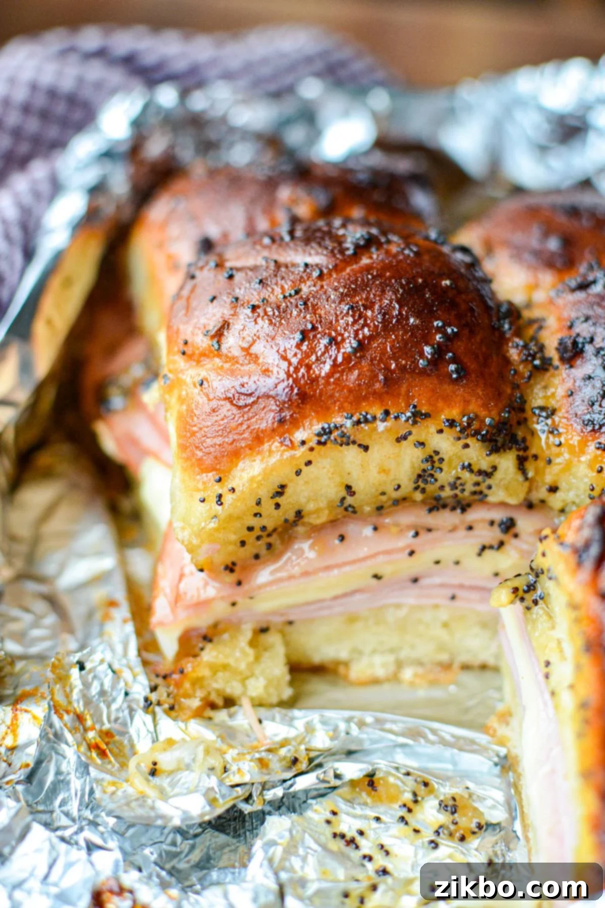 Golden Air Fryer Ham and Cheese Sliders 6 A tray of freshly baked ham and cheese sliders, nestled in aluminum foil, ready to be served.