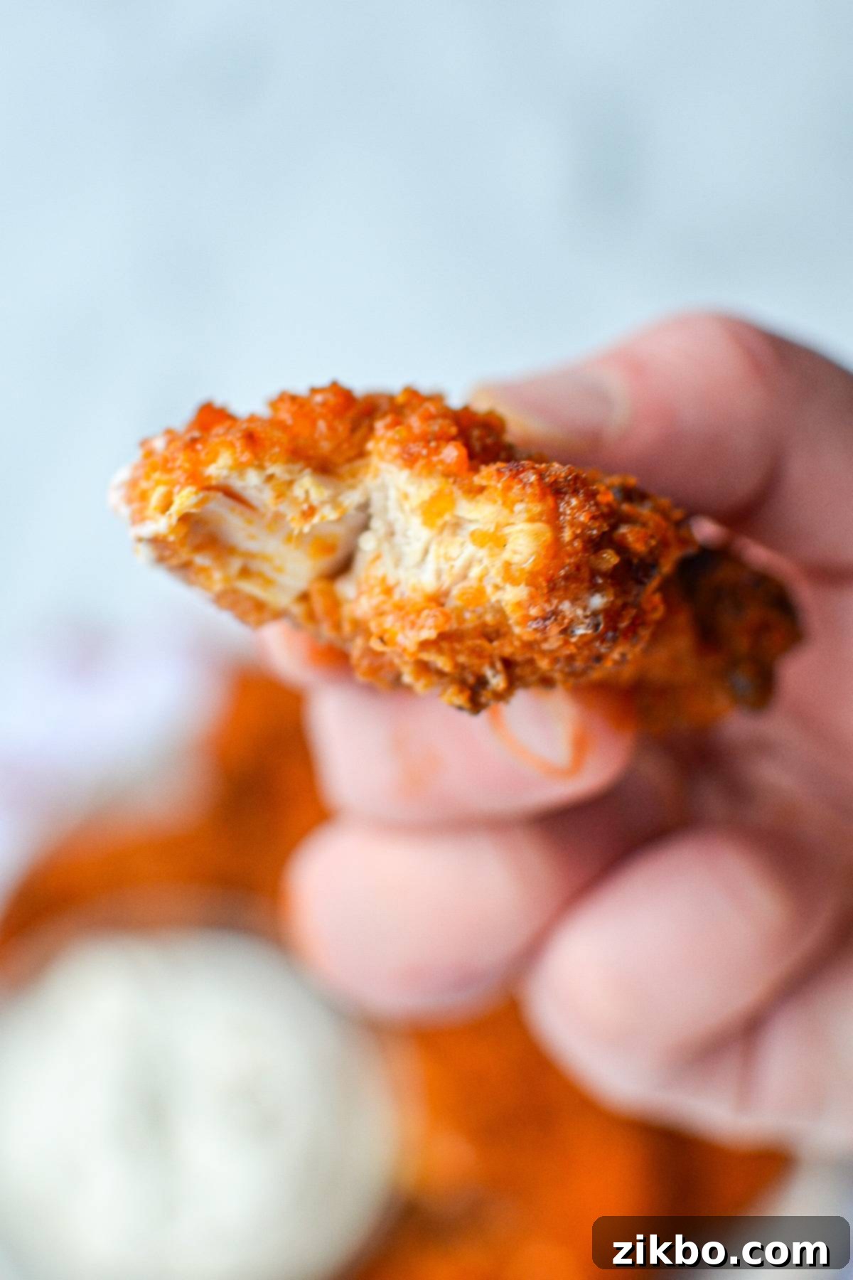 A piece of buffalo chicken tenders with a bite taken out of it.
