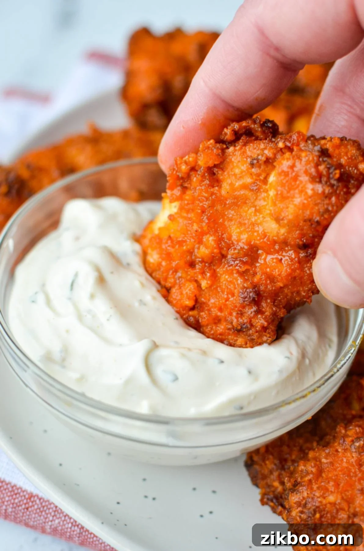 Dipping buffalo chicken tenders into a ranch dip.