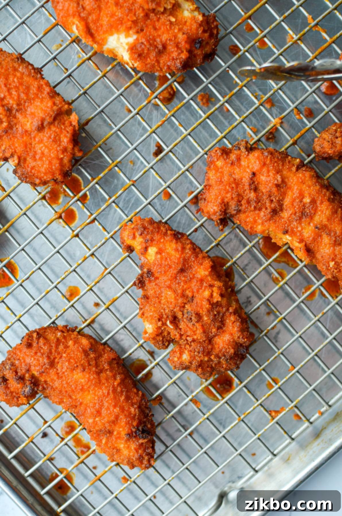 A wire rack with buffalo chicken tenders on it.