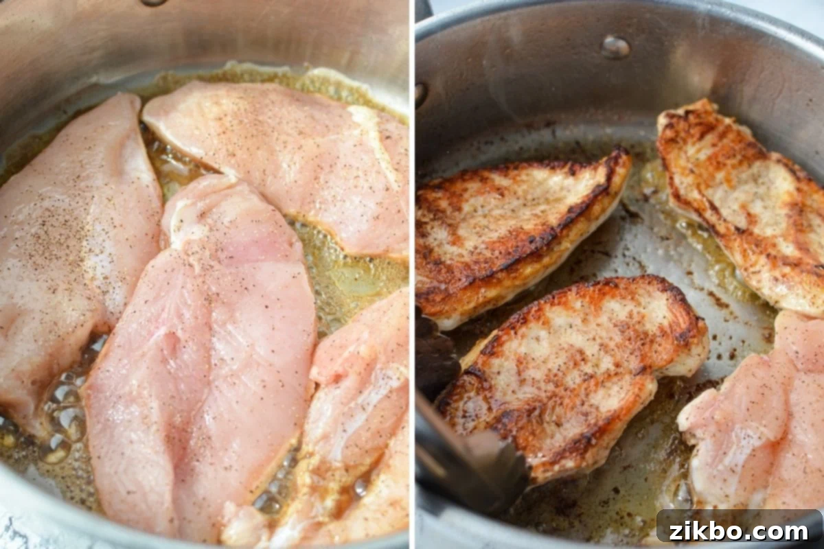 Browning the chicken on both sides in a hot skillet. Four chicken cutlets are searing in a hot skillet with melted butter, showing a golden-brown crust on one side.