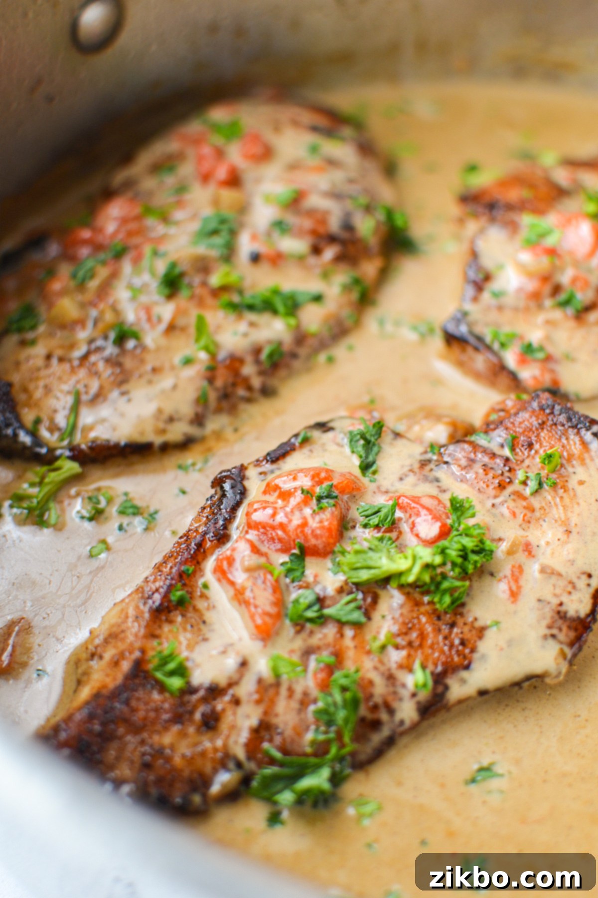 A close-up of a chicken breast perfectly coated in the rich, creamy roasted red pepper sauce, ready to be served.