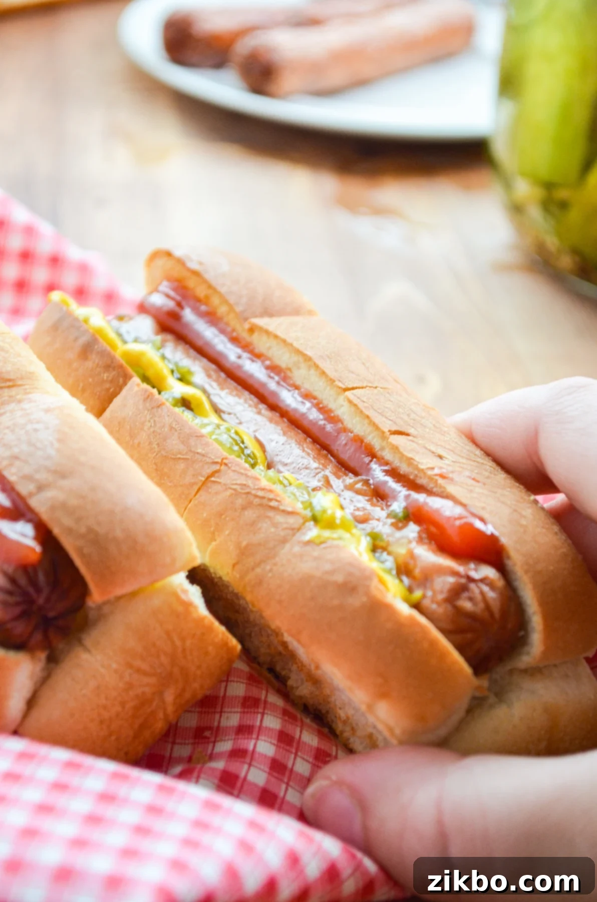 A hand reaching in for a fully dressed Air Fryer Hot Dog