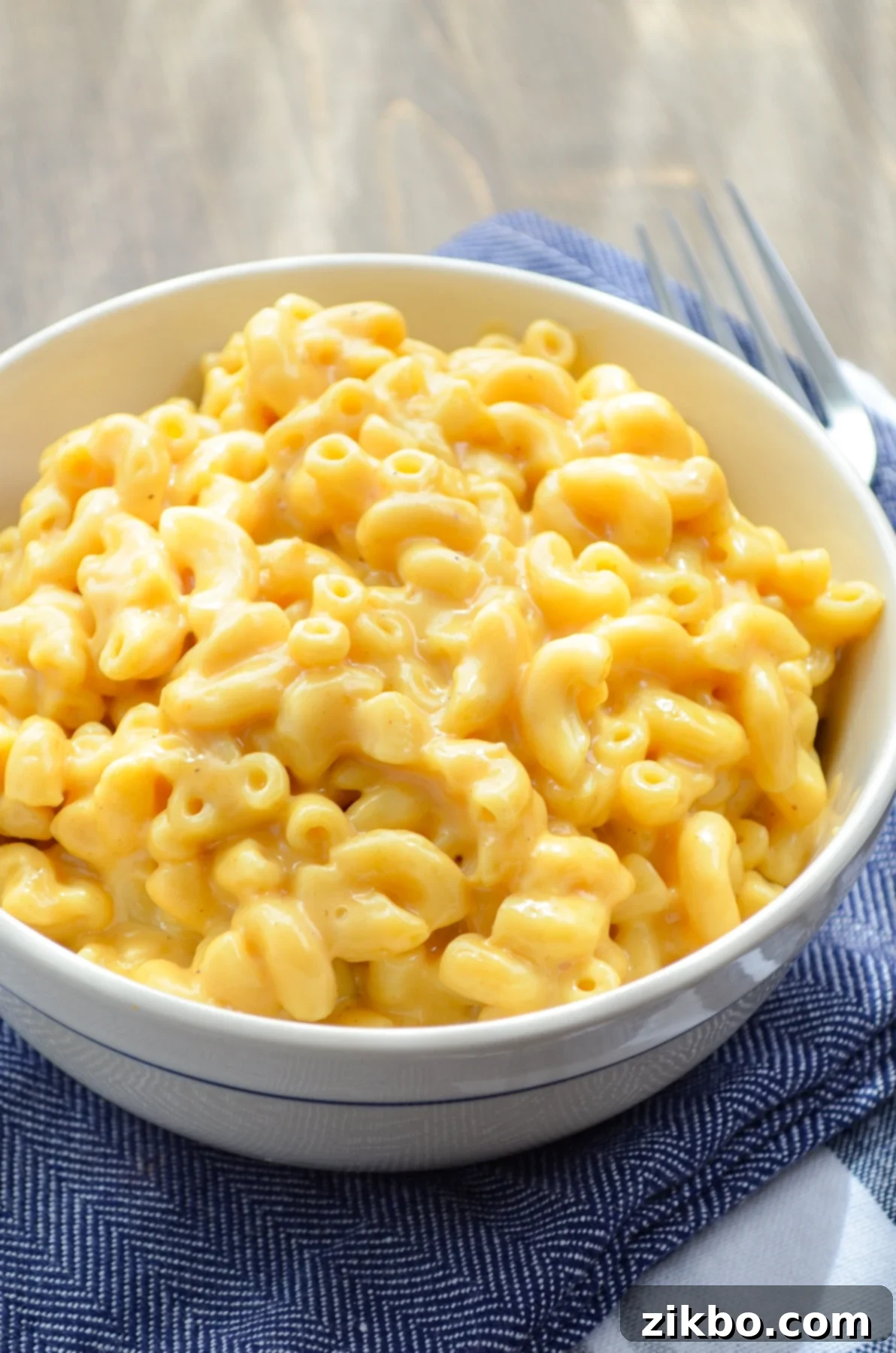 Quick and Creamy 5-Ingredient Instant Pot Velveeta Mac and Cheese 10 A beautifully plated bowl of macaroni and cheese, resting on blue napkins, ready to eat.