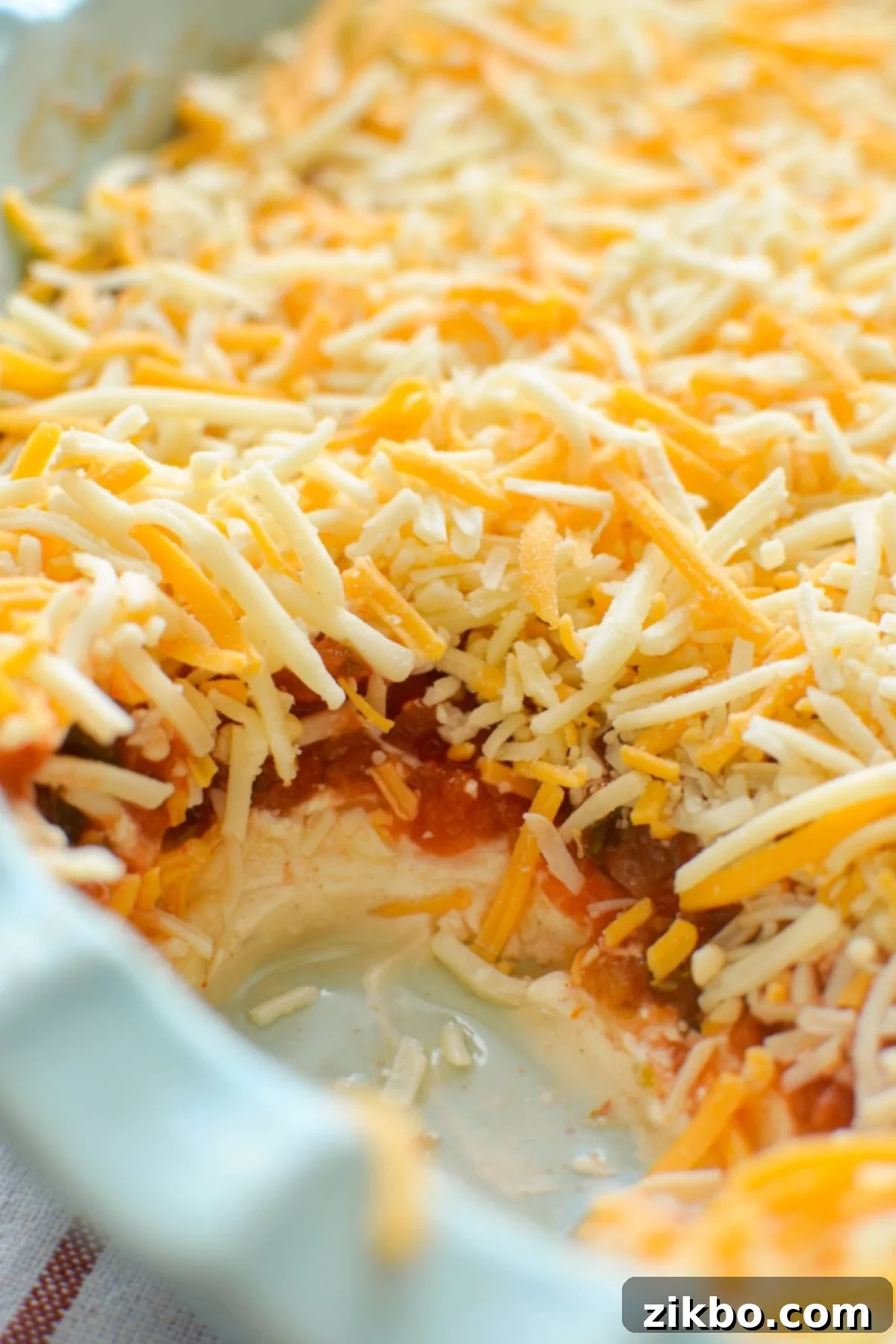 A close-up shot of a beautifully layered nacho dip in a serving bowl, showcasing its creamy, zesty, and cheesy textures, perfectly inviting for dipping.