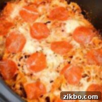 Slow Cooker Pizza Delight 8 A close up of a slow cooker filled with pizza casserole, topped with pepperoni and melted cheese, ready to be served.