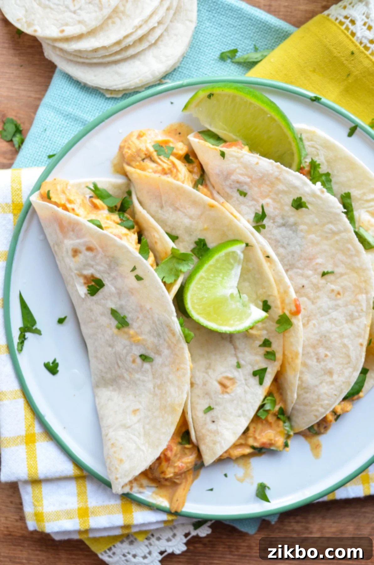Three chicken queso tacos on a plate, resting on bright napkins.