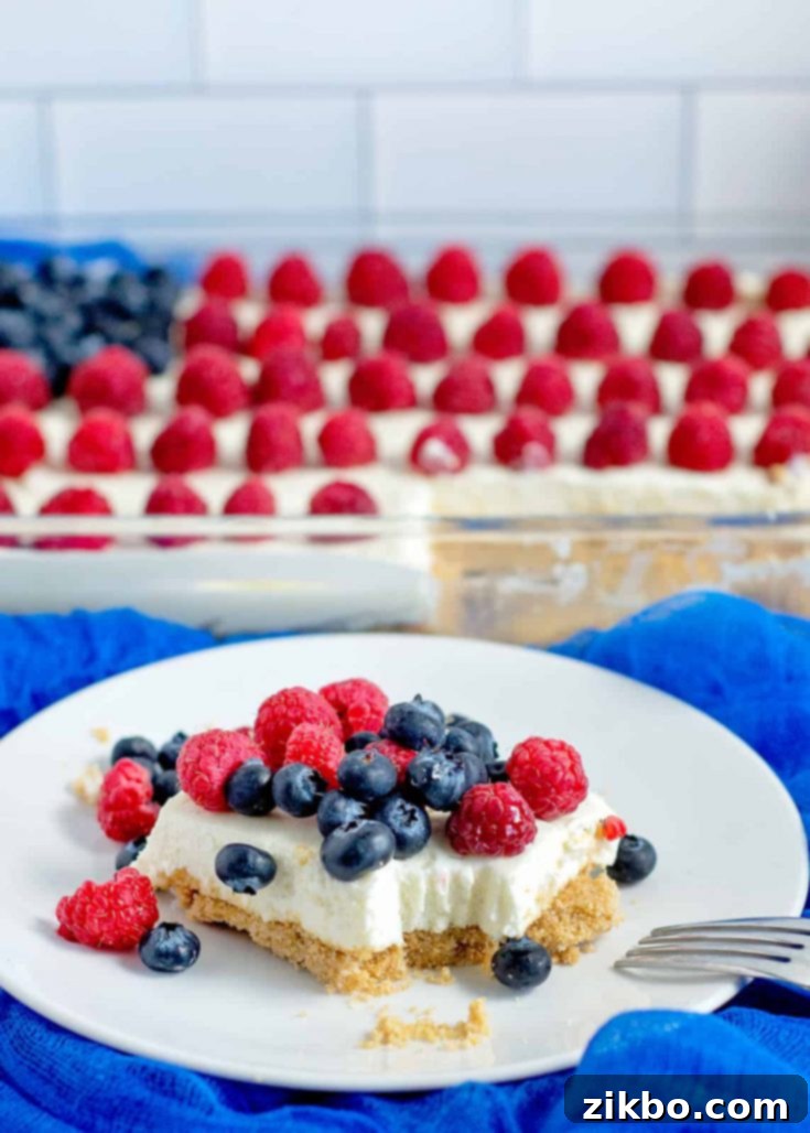 No-Bake Red, White, and Blue Cheesecake Bars, garnished with fresh red and blue berries, a creamy and easy patriotic treat.