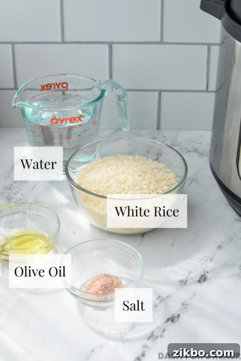 The essential ingredients needed to make fluffy Instant Pot white rice: long grain white rice, cool water, salt, and olive oil, laid out on a kitchen surface.