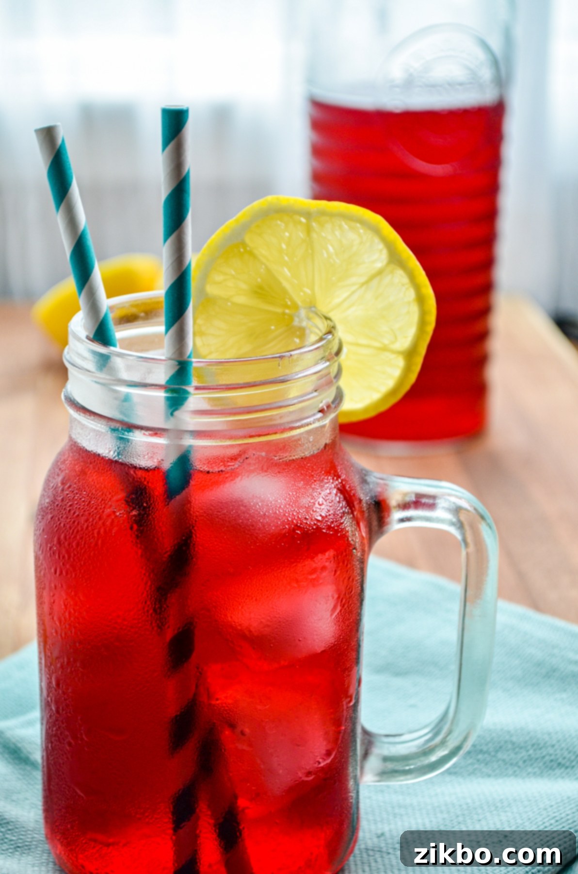 A big mug of passion tea lemonade served with a slice of Lemon, highlighting the refreshing pink color.