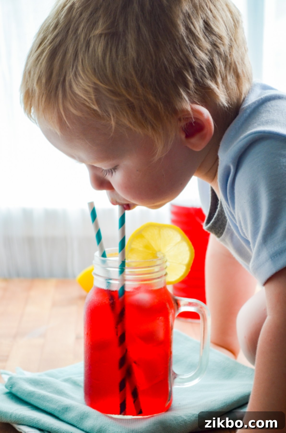A toddler happily taking a sip of the Instant Pot Passion Tea Lemonade, illustrating its family-friendly appeal.