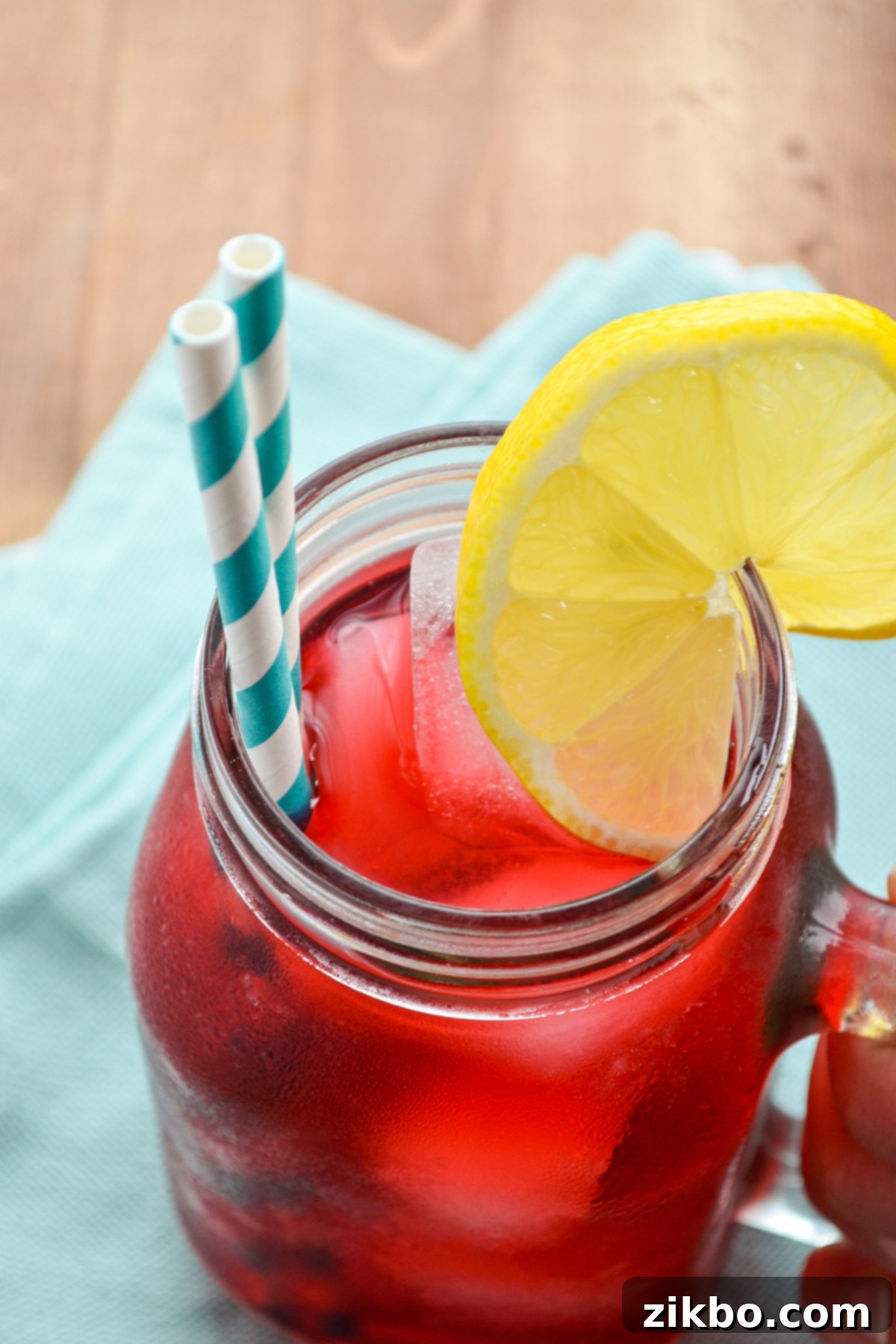 A vibrant glass of passion tea lemonade, beautifully garnished with a lemon wedge, ready to be enjoyed.