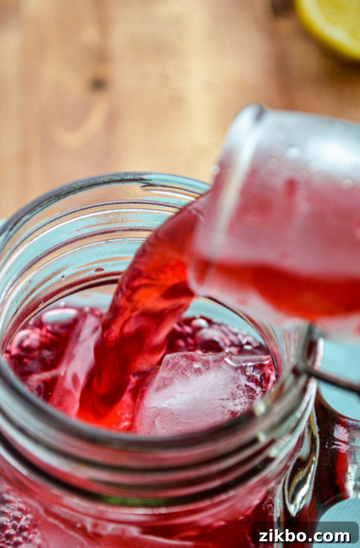 Pouring the freshly made Instant Pot Passion Tea Lemonade into a glass over ice.