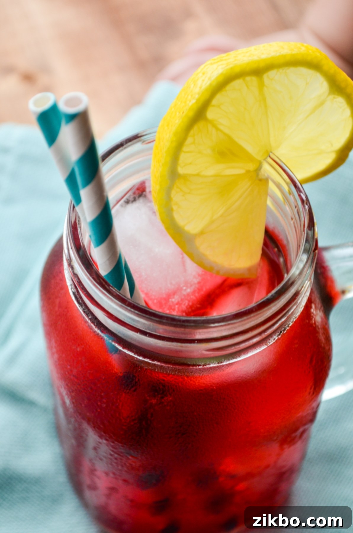A glass of Instant Pot Passion Tea Lemonade served outdoors with a lemon wedge, emphasizing its refreshing quality.