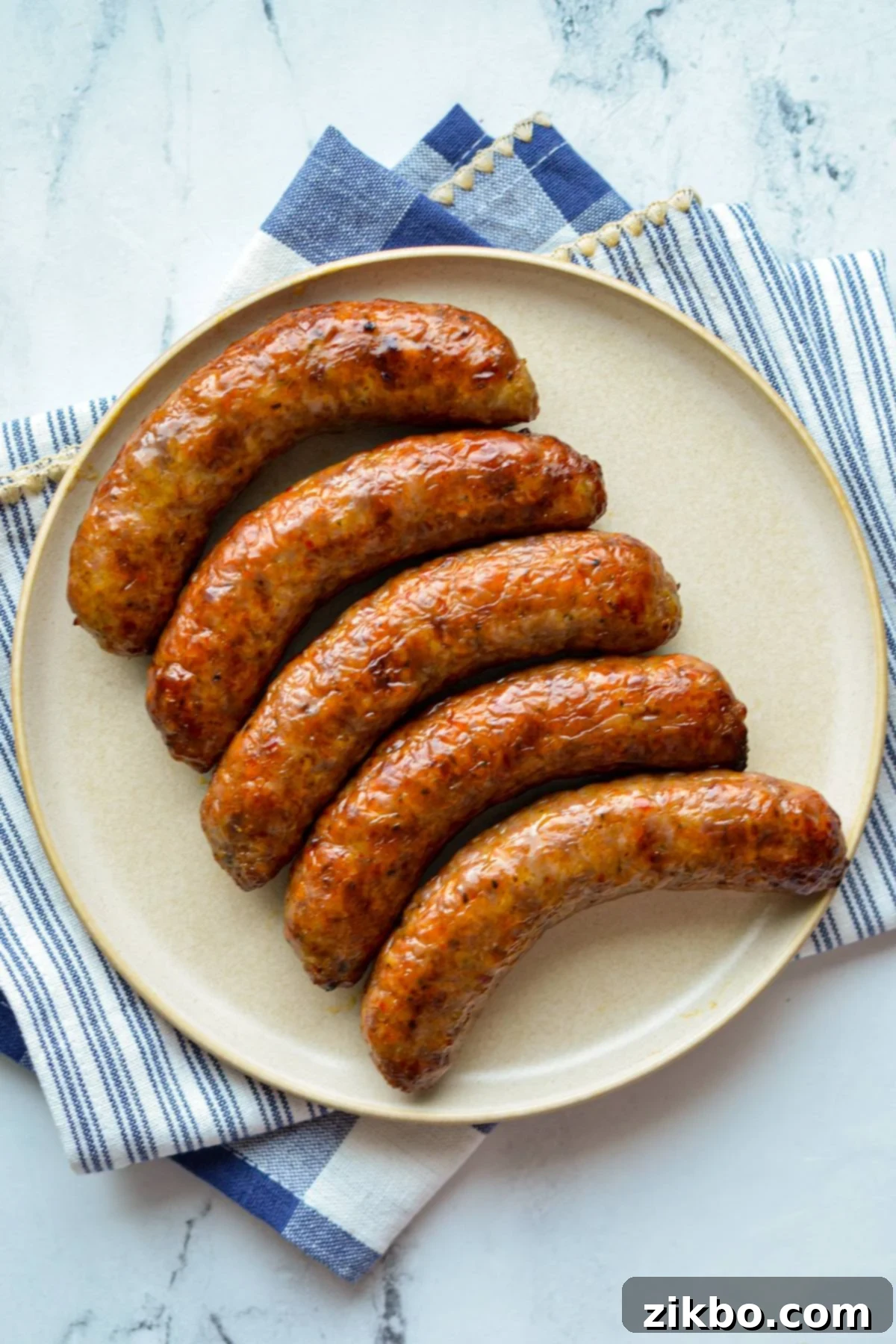 An overhead shot of a plate with cooked sausages on it.