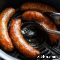 An air fryer basket with Italian sausages, being lifted out with tongs.