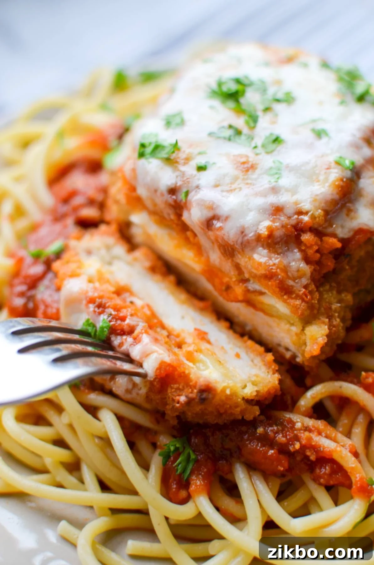 A fork taking a piece of chicken parmesan.