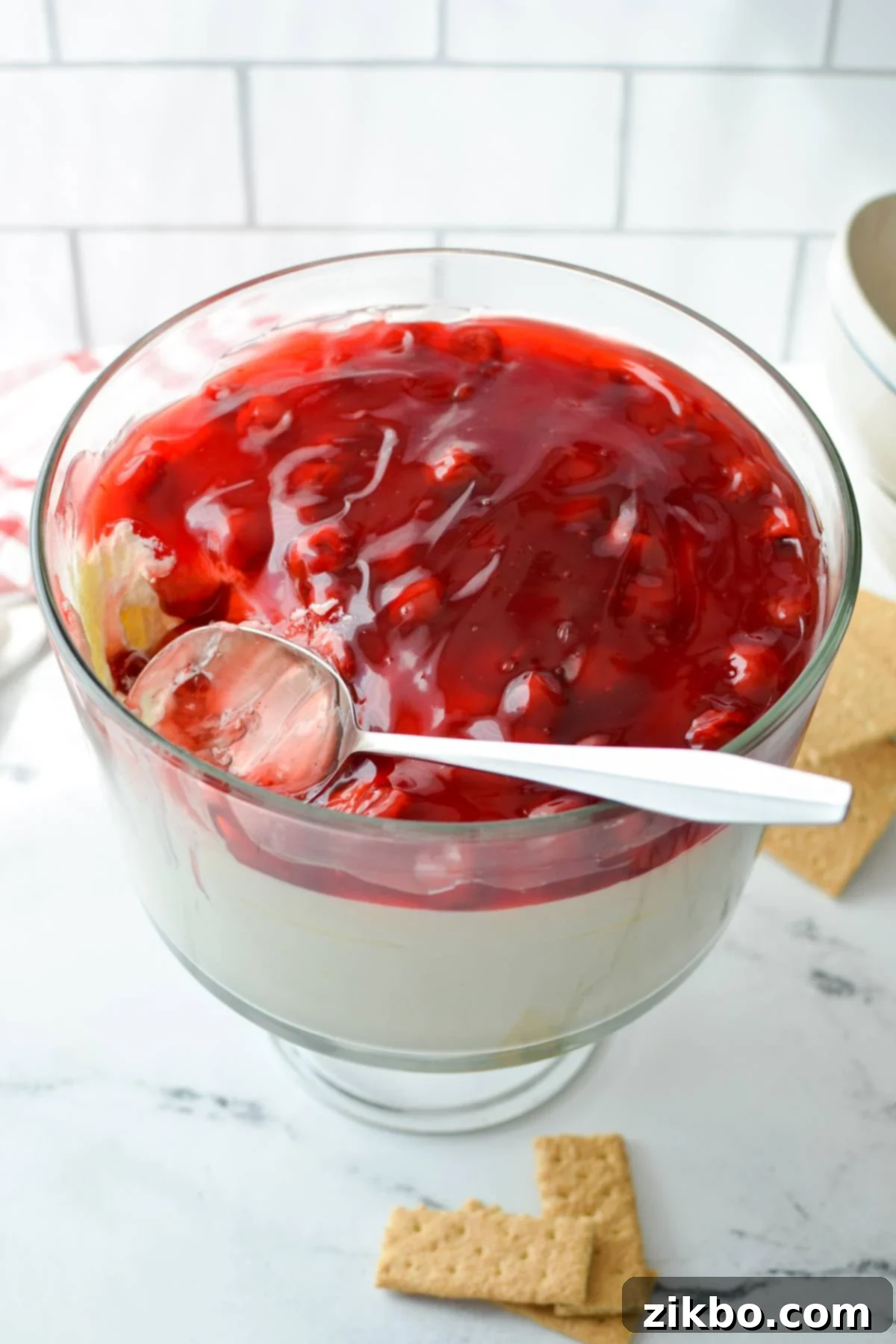 A large, ornate trifle dish generously filled with a layered dessert dip, showcasing its beautiful presentation.