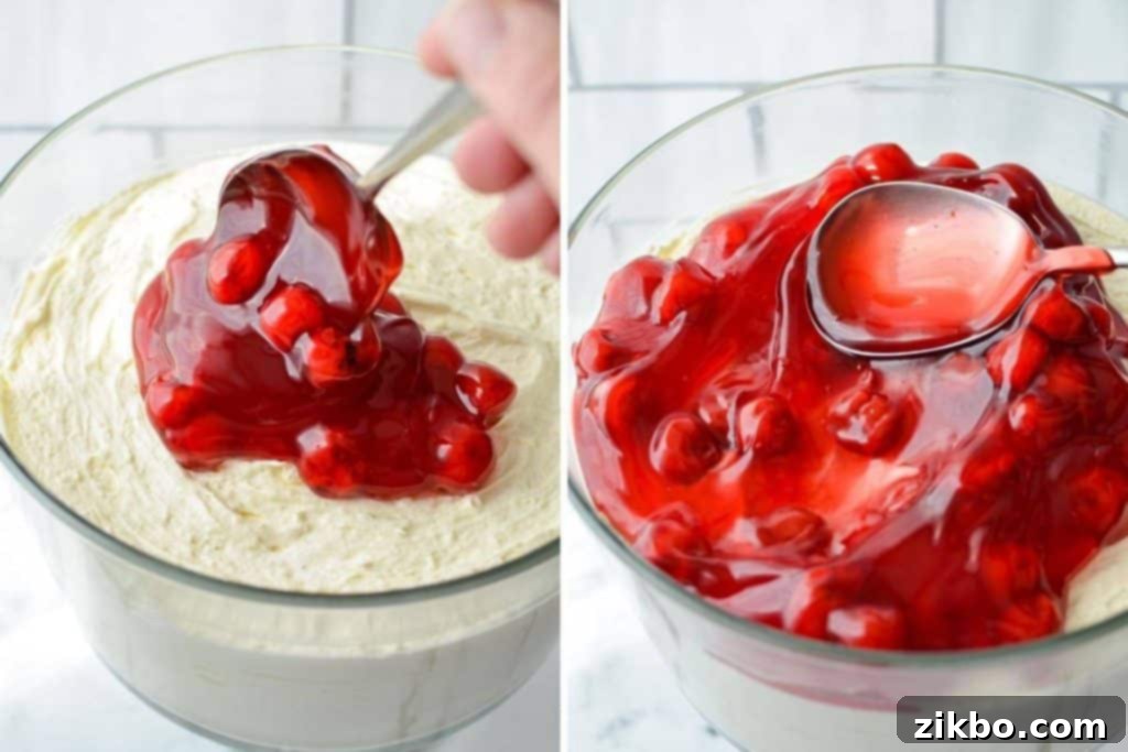 Adding a generous layer of vibrant pie filling on top of the creamy no-bake cheesecake base.