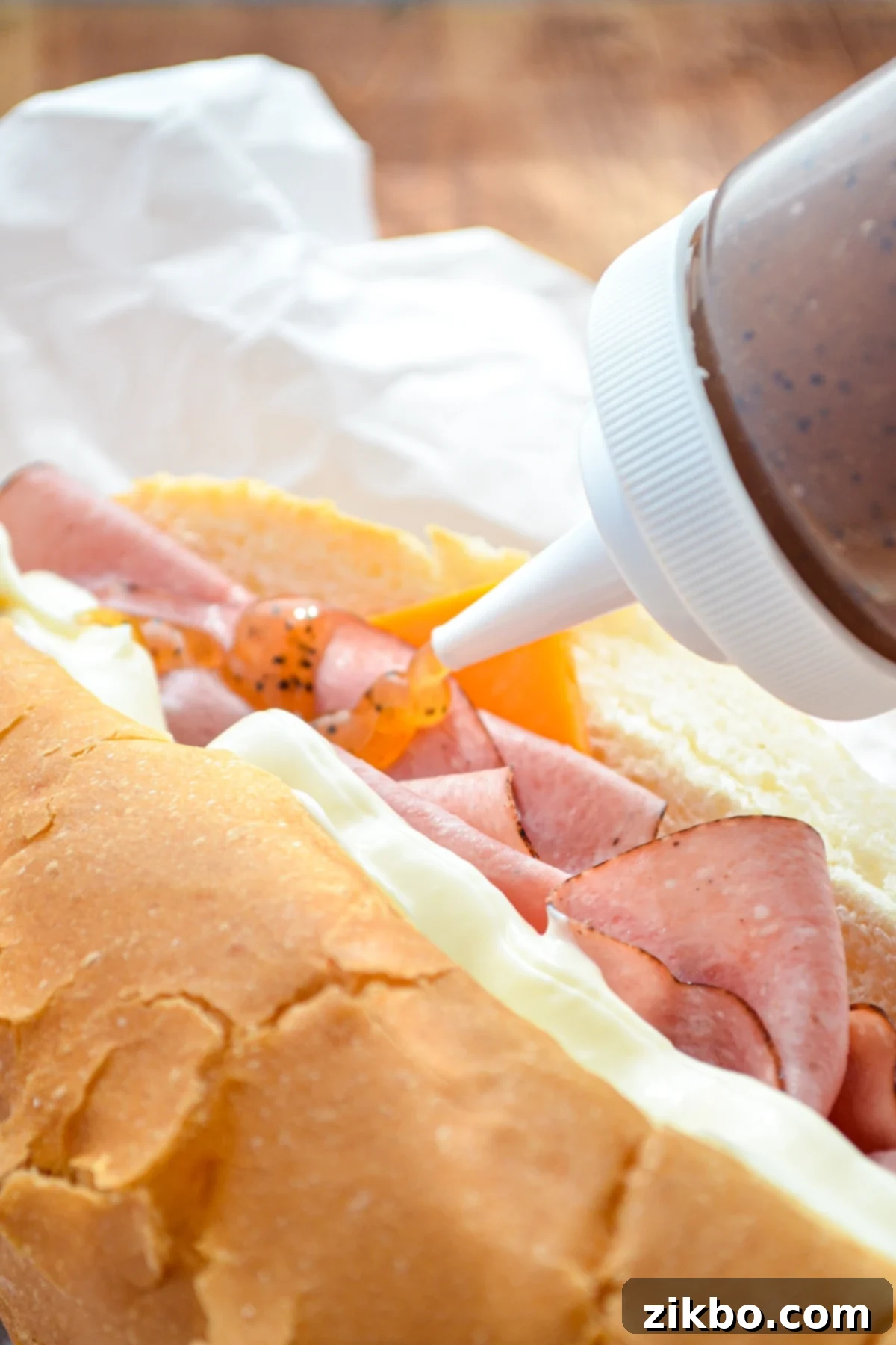 Sweet onion sauce being squeezed onto a homemade sub.