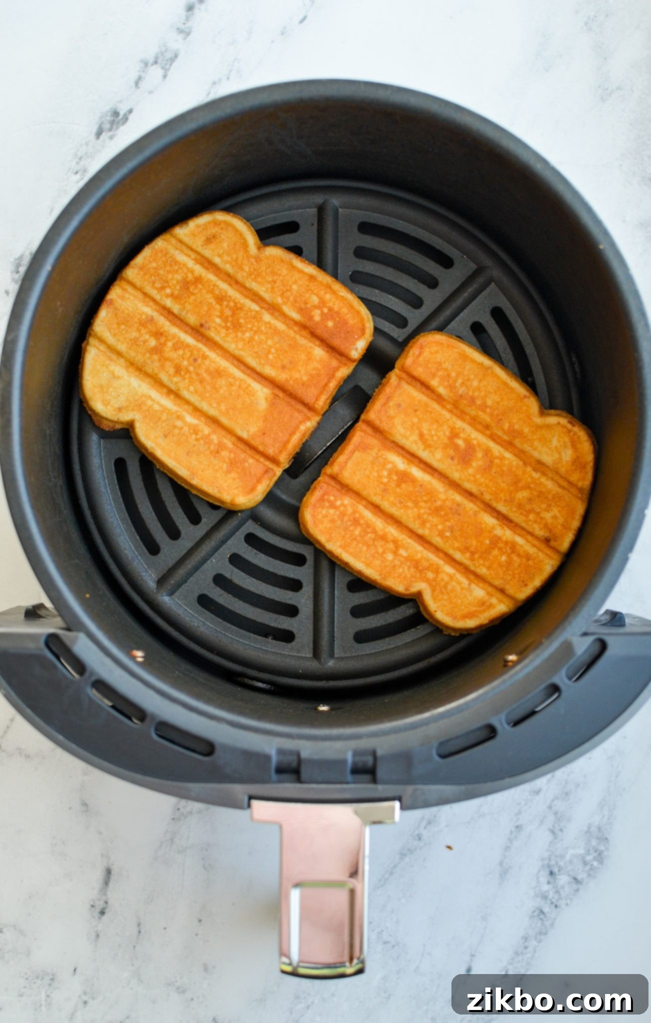 Perfectly browned and crispy French toast sticks resting in an air fryer basket after cooking.