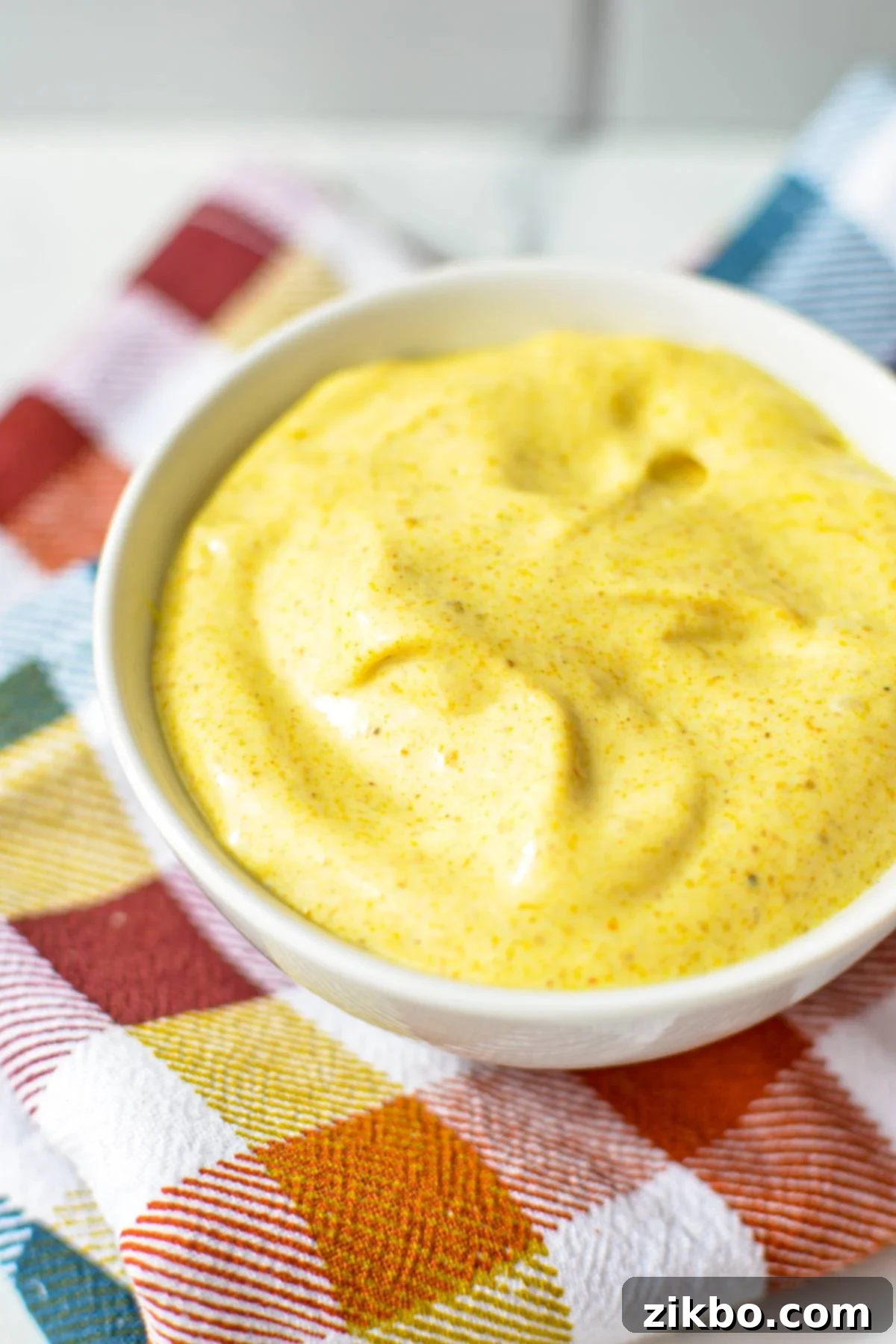 A small bowl of creamy yellow homemade curry mayonnaise, perfectly smooth and ready to serve.