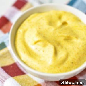A small bowl of golden homemade curry aioli, perfectly smooth and ready to be served as a delicious dipping sauce.