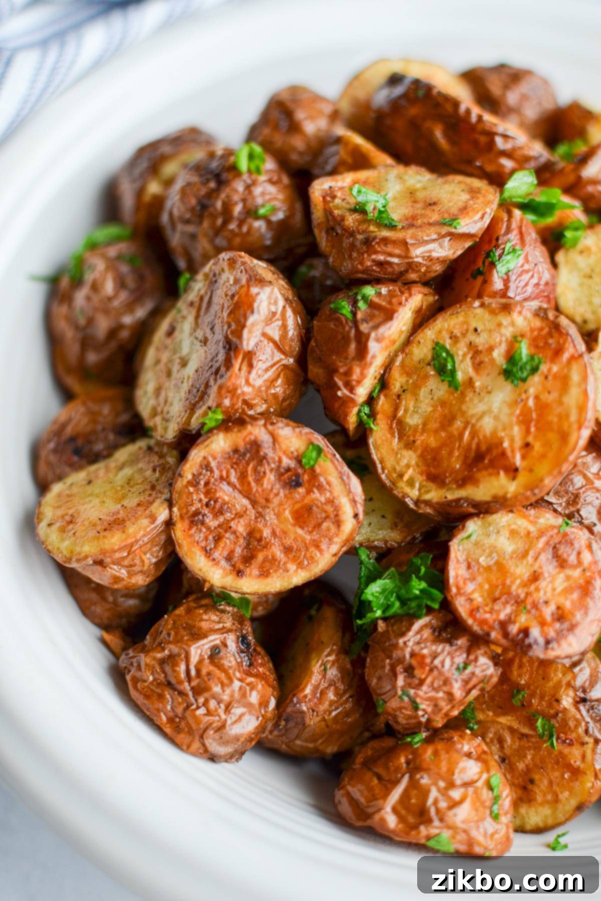 A bowl of perfectly roasted baby potatoes, garnished with fresh herbs, showcasing their golden-brown and crispy exterior.