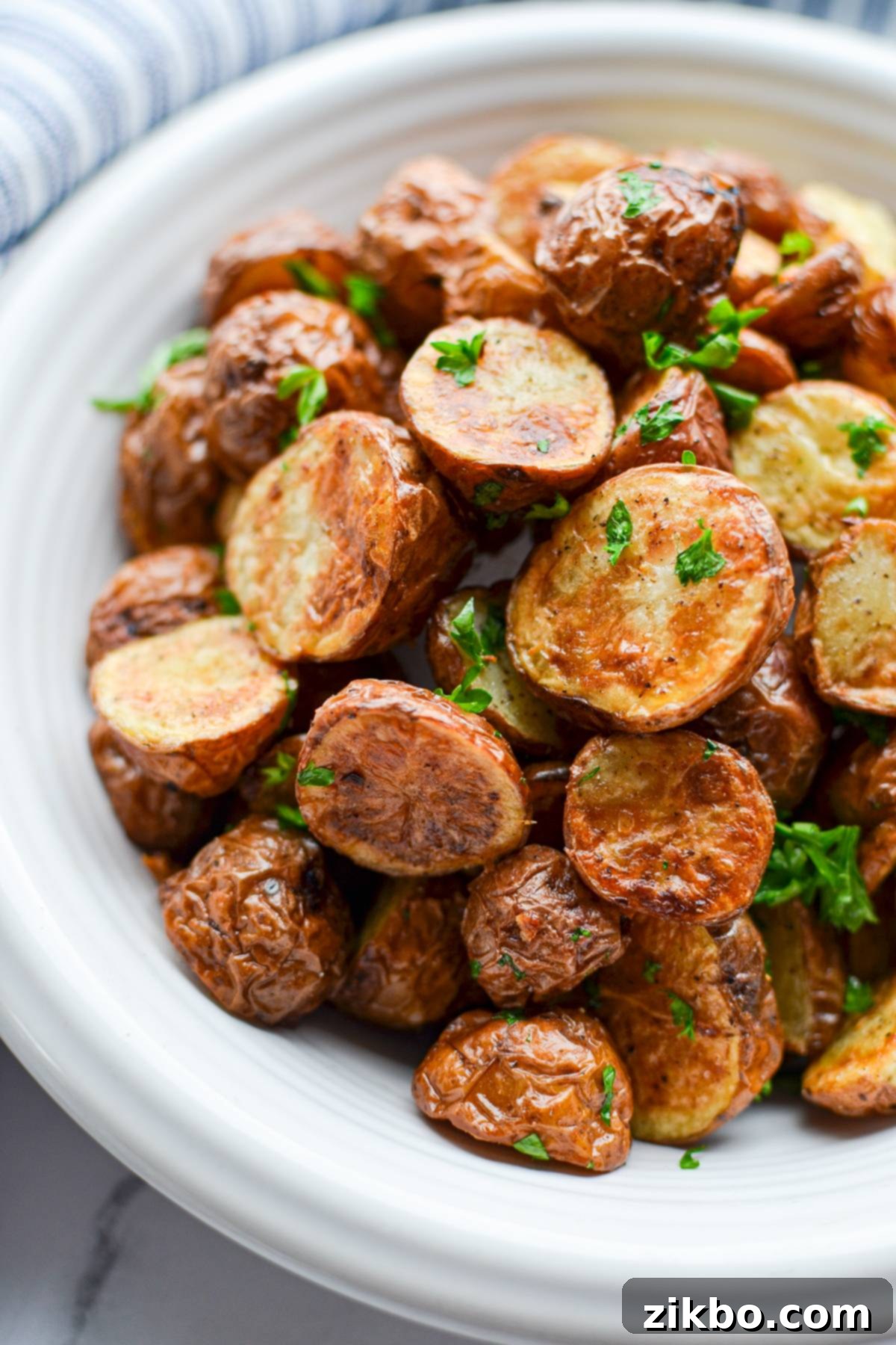 A vibrant bowl of cooked baby potatoes with fresh green parsley on top, ready to be served.