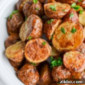 A bowl of halved and roasted baby potatoes garnished with fresh parsley, highlighting the golden crispiness.