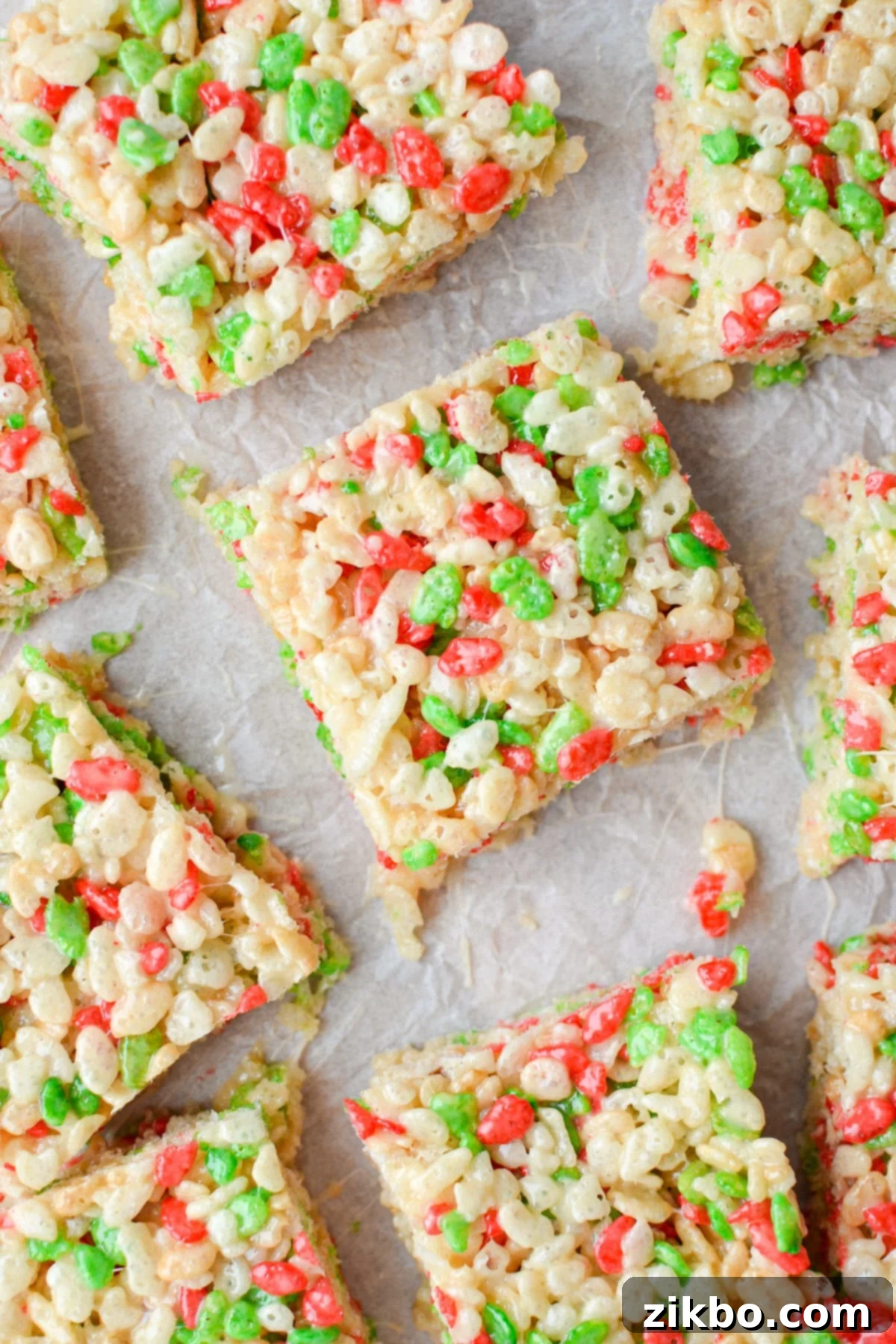 An overhead view of holiday Rice Krispie treats on a parchment lined baking sheet.