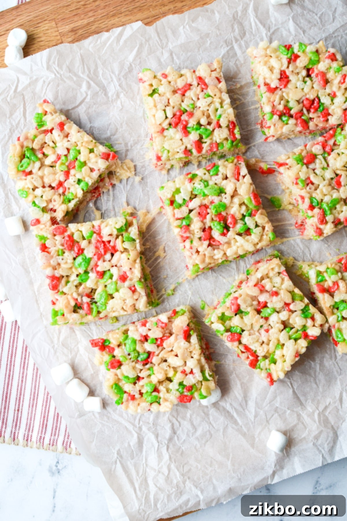 9 cereal treats place on a piece of parchment on top of a cutting board.