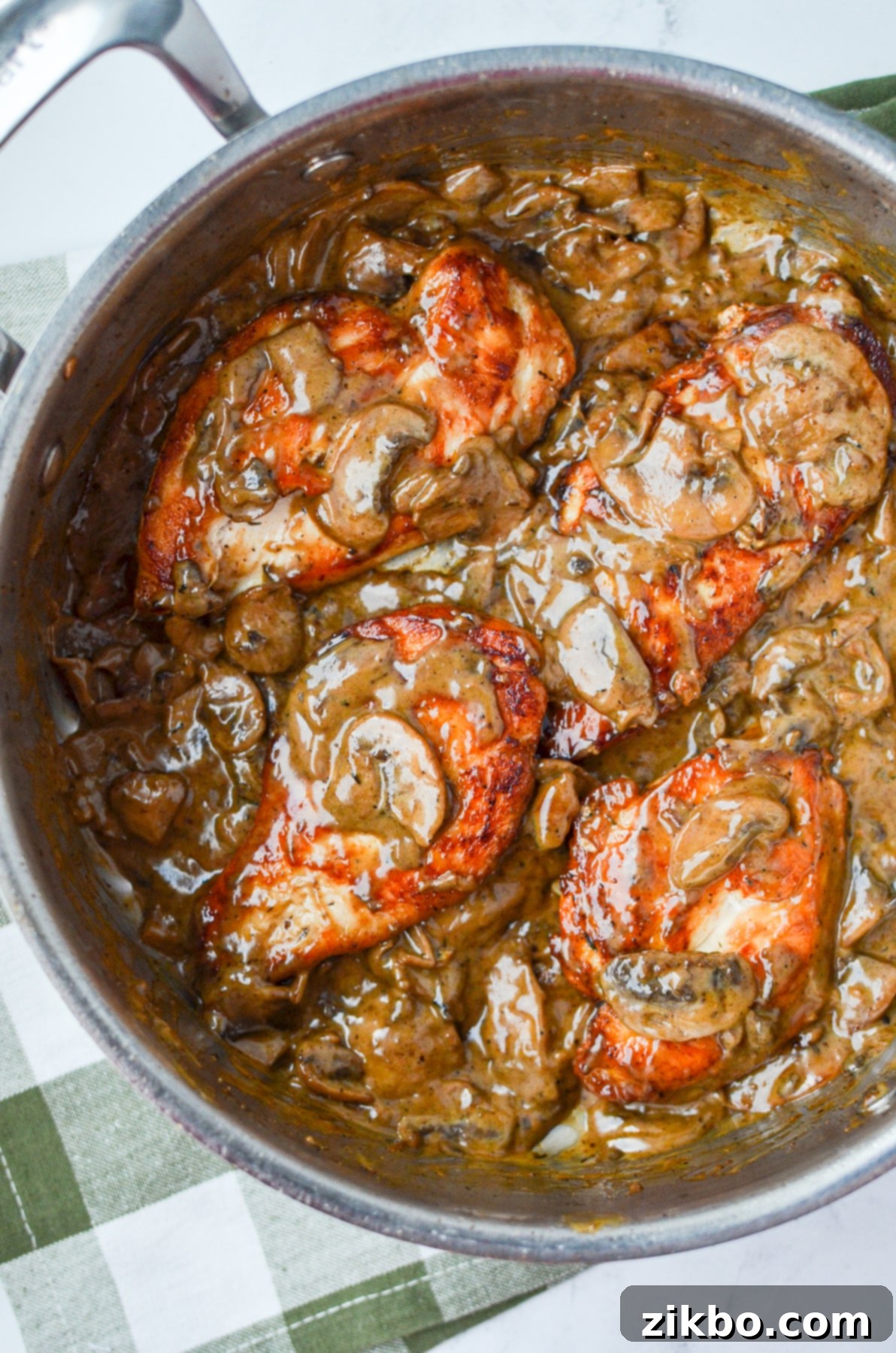 A skillet with chicken breasts and creamy mushroom sauce.