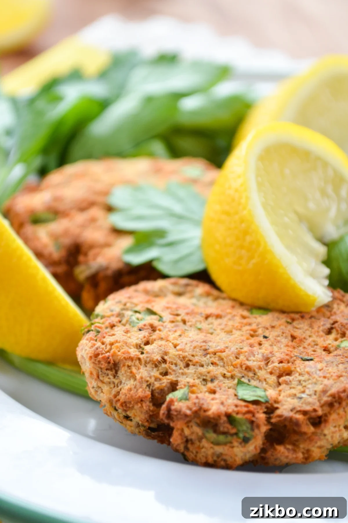 A plate of salmon patties, garnished with parsley and lemon wedges.